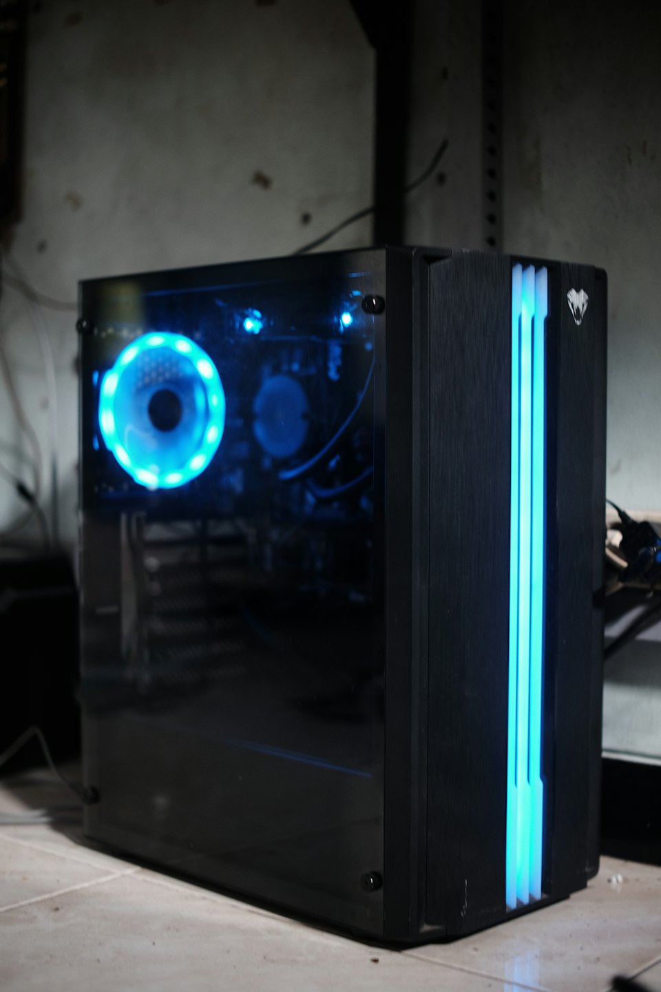 Schwarzer Gaming-Computer-Tower mit blauen Lichtern auf dem Boden.