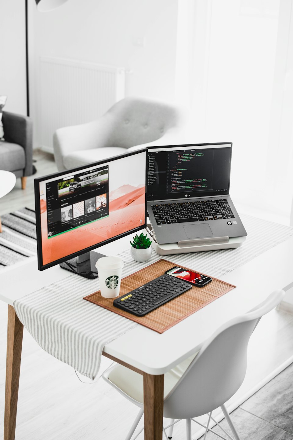 Moderner Homeoffice-Arbeitsplatz mit Laptop, externem Monitor mit Code und Schreibtischzubehör.