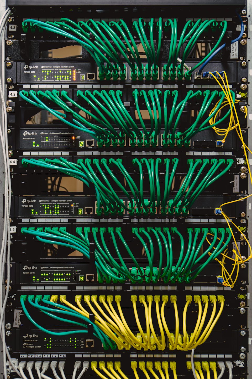 Gestapelte Netzwerk-Switches mit vielen eingesteckten Ethernet-Kabeln.