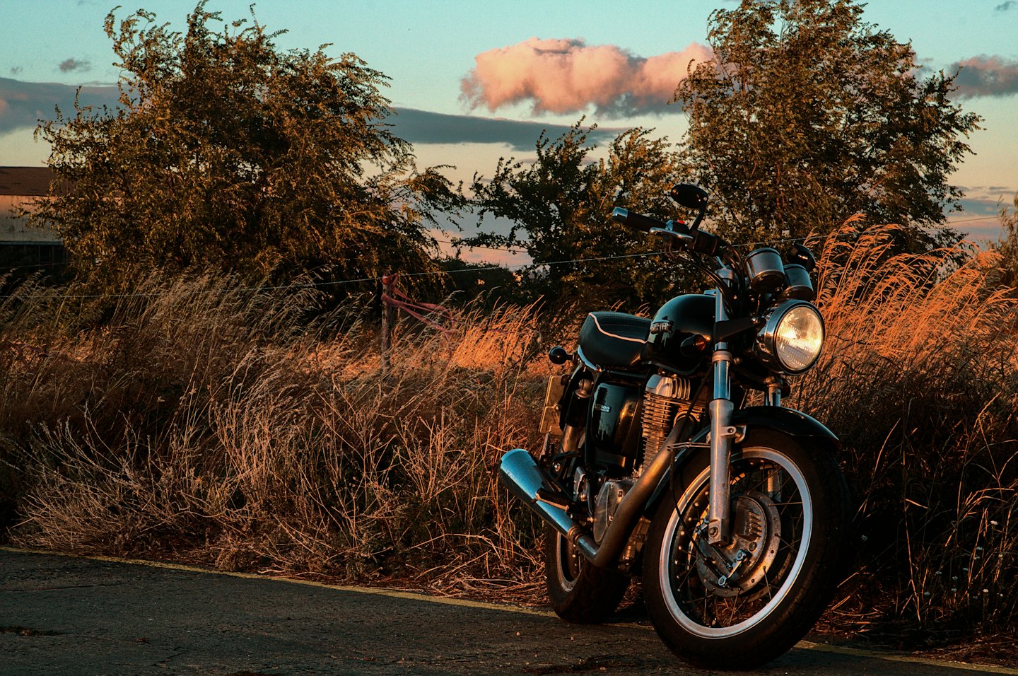 Klassische Motorradpark am Straßenrand bei Sonnenuntergang mit goldenem Gras.